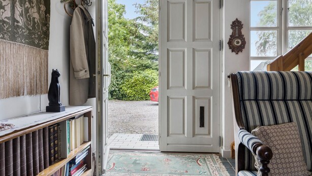 A room with a bookshelf, a patterned rug, a chair with a cushion, and a door leading outside. - Nice home in Sønderborg with kitchen (Sønderborg)