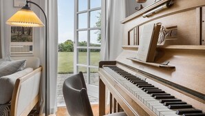 A piano room with a view to the outdoors, a lamp, and a framed certificate on the wall. - Nice home in Sønderborg with kitchen (Sønderborg)