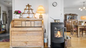 A cozy living room with a wooden dresser, a modern fireplace, and a dining area with wooden furniture. - Nice home in Sønderborg with kitchen (Sønderborg)