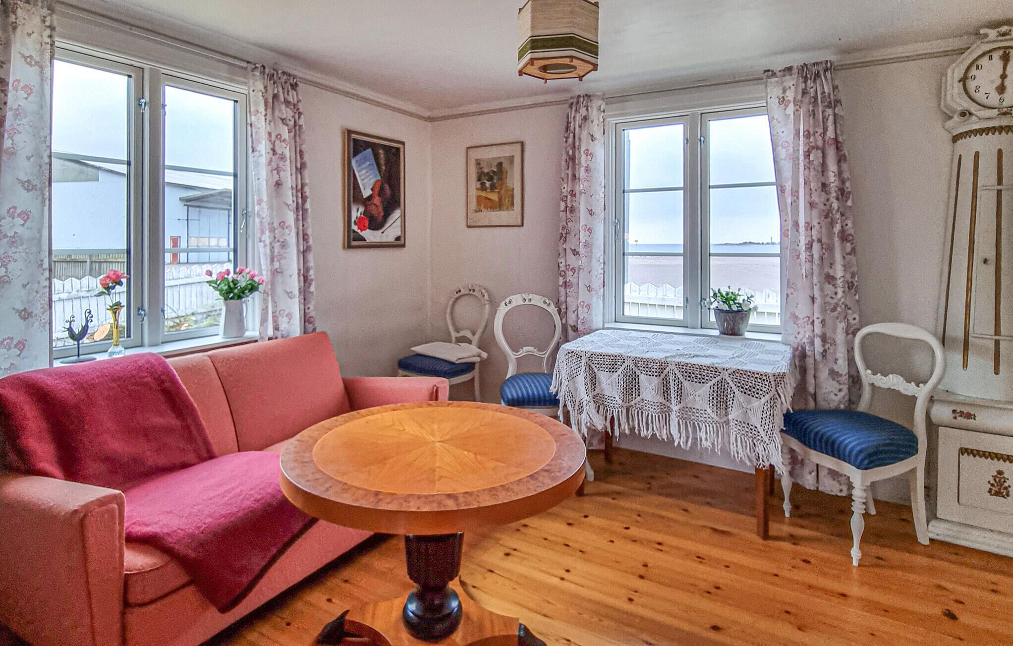 Ett mysigt rum med ett runt träbord, en rosa soffa och ett vitt skåp.
