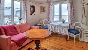 Una habitación acogedora con una mesa redonda de madera, un sofá rosa y un armario blanco.