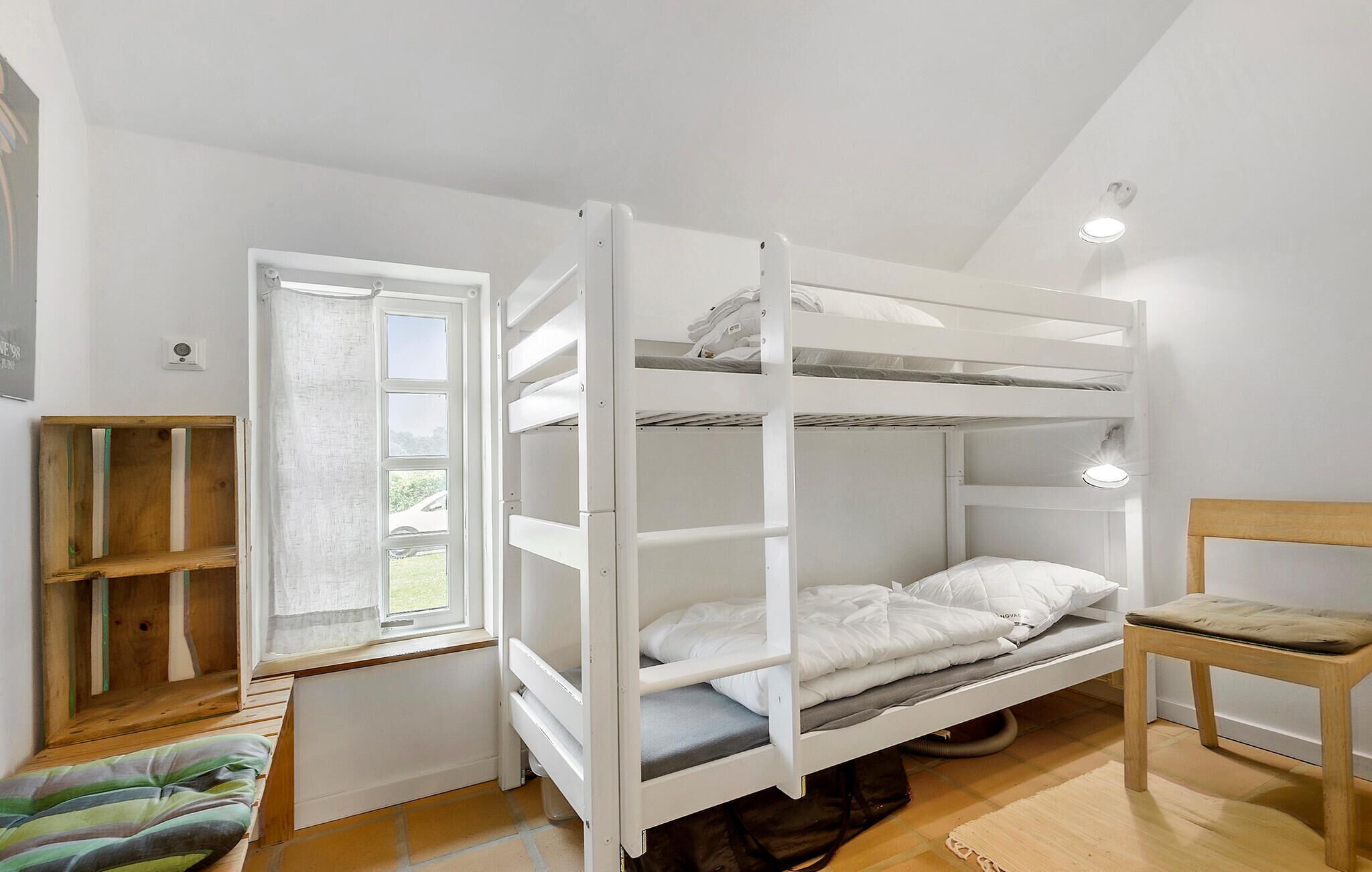 A bunk bed room with a window, a wooden chair, and a radiator.