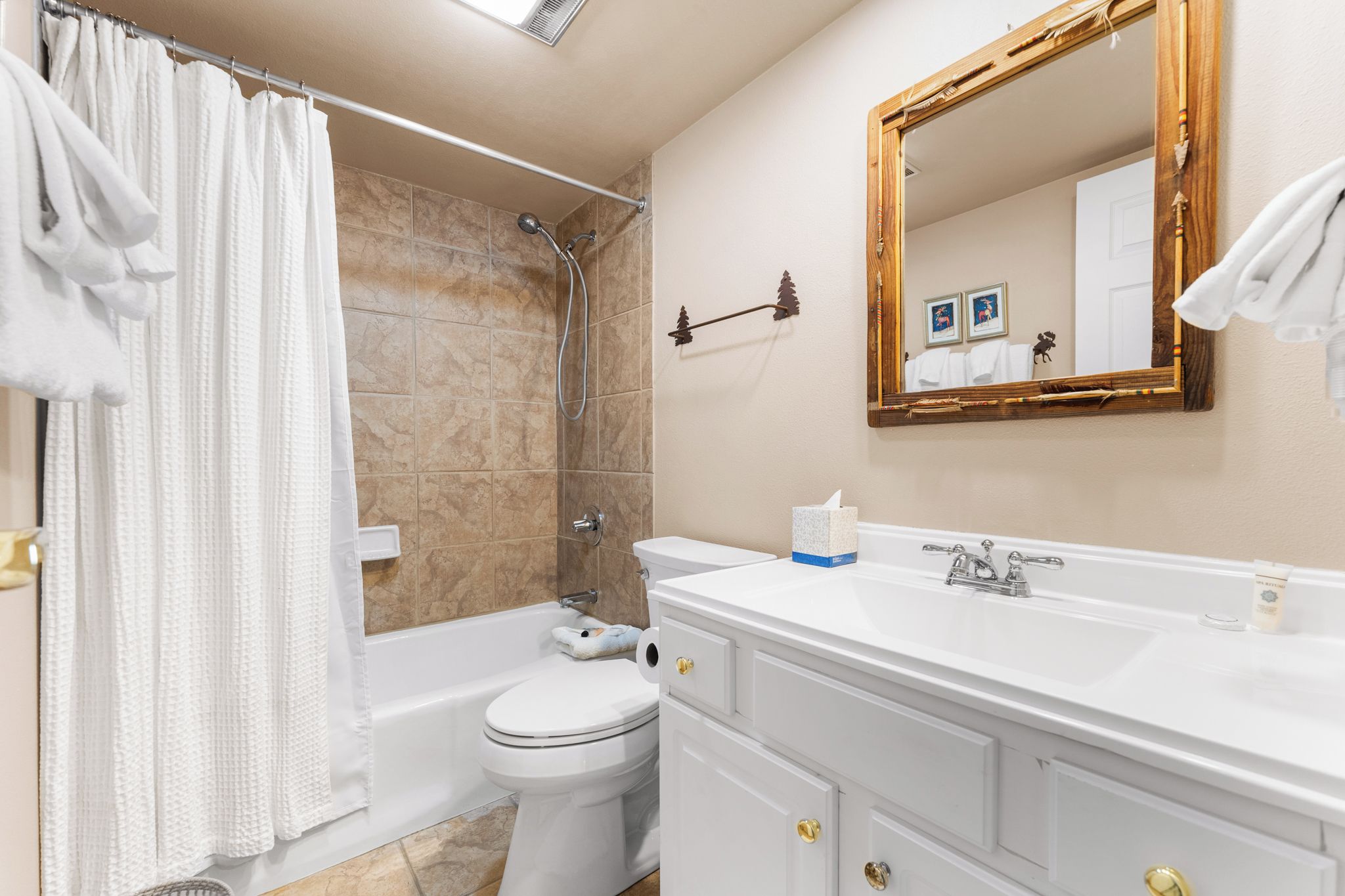 A bathroom with a bathtub, toilet, sink, and a mirror.