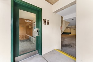 Entrada de estacionamento com porta verde, vagas numeradas e piso de concreto.