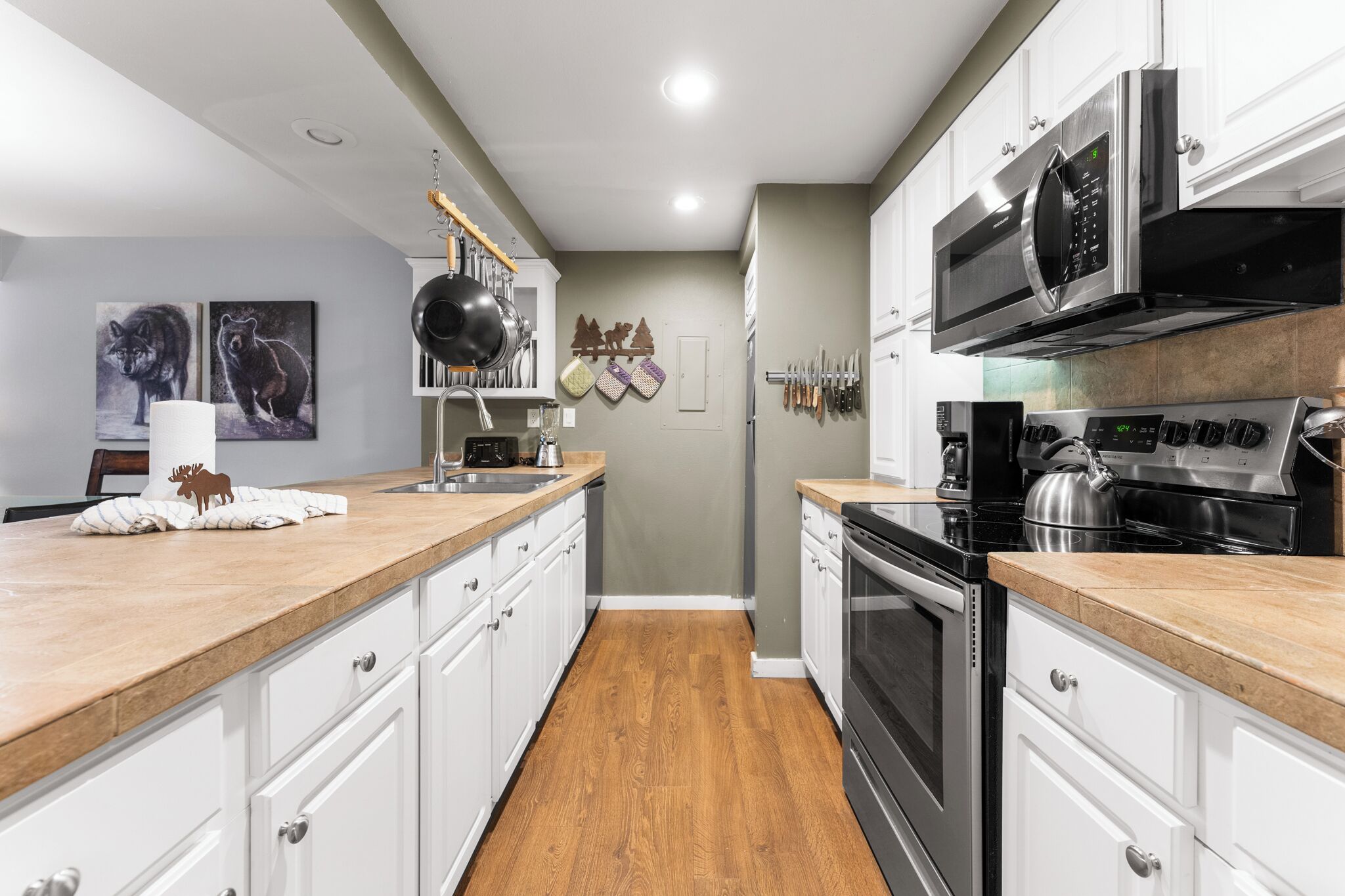 A modern kitchen with white cabinets, a wooden countertop, stainless steel appliances, and a backsplash.