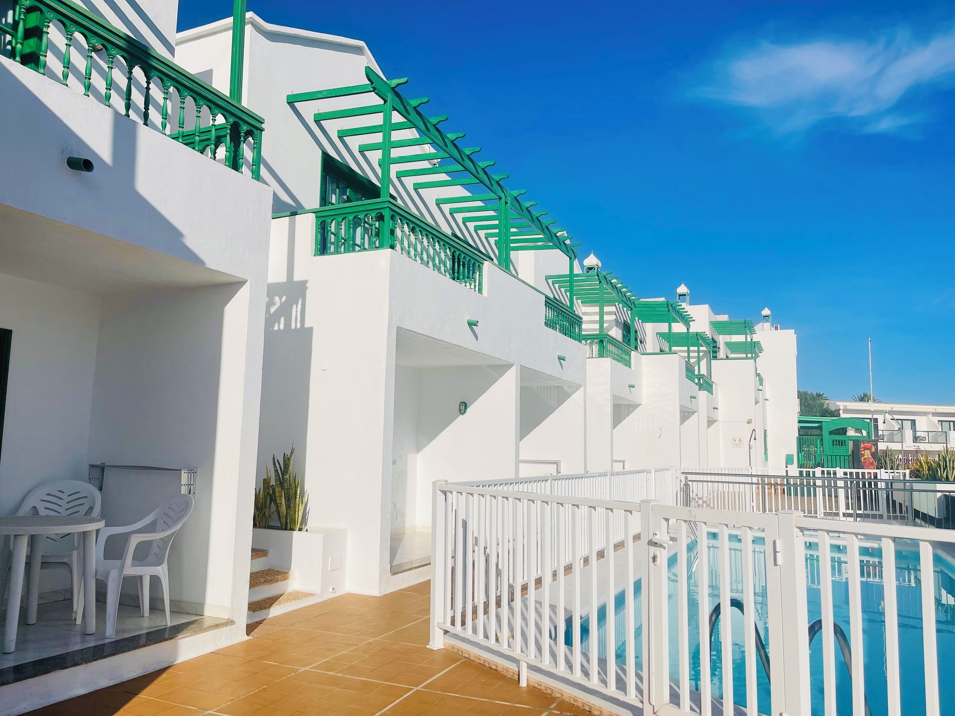 A white building with green railings and a pool area.