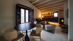 Un salon chaleureux avec un plafond en bois, une cheminée, un canapé et une table à manger avec des chaises.
