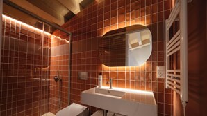 Une salle de bain moderne avec une douche à parois de verre, un lavabo blanc avec un miroir et des toilettes.