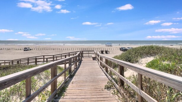 A wooden boardwalk leading to a beach with a clear sky.