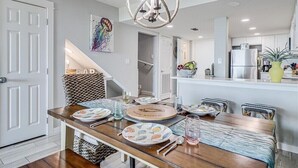 A modern kitchen with white cabinets, a stainless steel refrigerator, and a hanging light fixture.