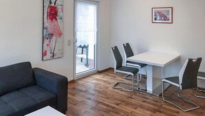 Ett modernt vardagsrum med en soffa, ett matbord med stolar och ett stort fönster.