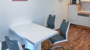 Ett modernt kök med vita skåp, en mikrovågsugn och en diskho.