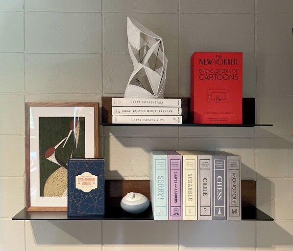 A bookshelf with books and decorative items, including a framed artwork and a small white object.