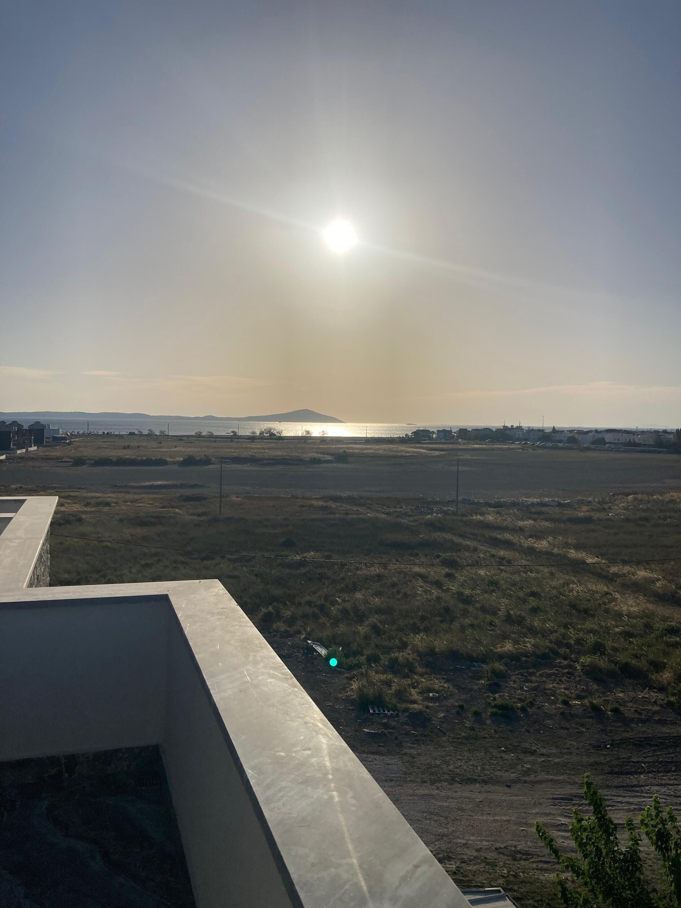 A view from a balcony overlooking a flat landscape with a distant mountain and a body of water.