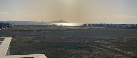 A view from a balcony overlooking a flat landscape with a distant mountain and a body of water.