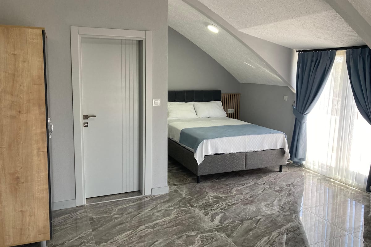 Un dormitorio con una cama, una puerta y una ventana con cortinas.