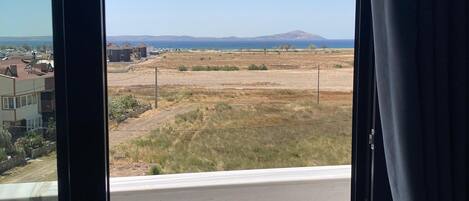 A view from a balcony with a clear sky, a distant mountain, and a road in the foreground.