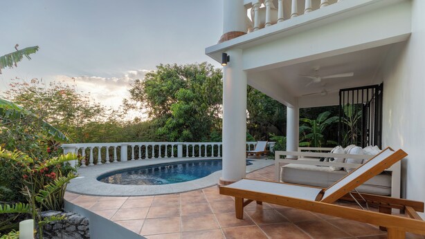 A poolside area with a curved pool, lounge chairs, and a covered seating area. - 2 BDR Ocean View Apt. in Pelada (Provincia de Guanacaste)