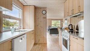 Eine moderne Küche mit Holzschränken, einem Edelstahlbackofen und einer Kaffeemaschine.