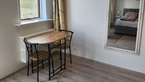 Una habitación con una mesa y sillas de madera, un radiador, una ventana con vistas y un espejo en la pared.