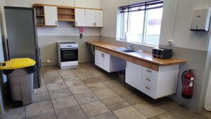 Una cocina funcional con refrigerador, horno, lavamanos y ventana.