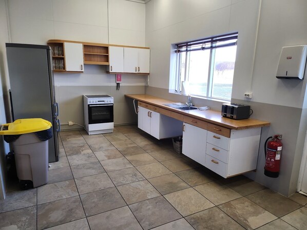 Una cocina funcional con refrigerador, horno, lavamanos y ventana.
