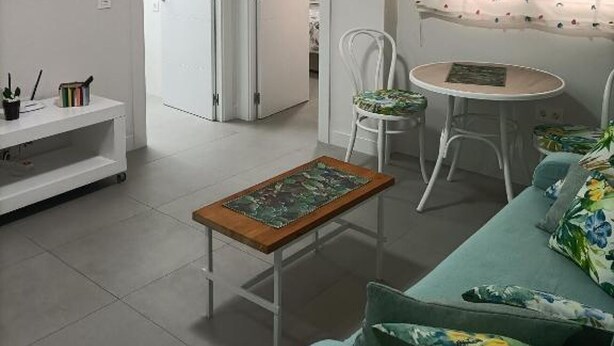 Een woonkamer met een bank, een salontafel, een televisie en een raam met gordijn.