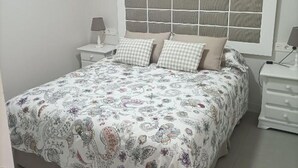 Een slaapkamer met een groot bed, twee nachtkastjes, een hoofdbord met een rasterpatroon en een wandairconditioning.