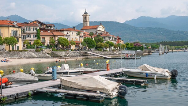 A lakeside town with boats docked at a pier, a church with a bell tower, and mountains in the background. - 1 bedroom gorgeous home in Baveno (Baveno)