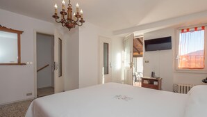 A bedroom with a large bed, a chandelier, a TV, and a window with curtains. - 1 bedroom gorgeous home in Baveno (Baveno)