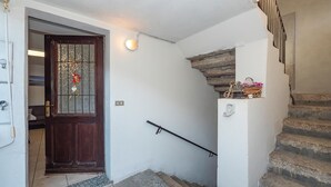 A staircase with stone steps leading to a landing, a wooden door with a glass panel, and a small shelf with decorative items. - 1 bedroom gorgeous home in Baveno (Baveno)