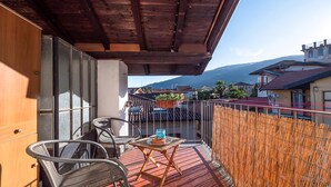 A balcony with wicker chairs, a small table, and a view of a town and mountains. - 1 bedroom gorgeous home in Baveno (Baveno)
