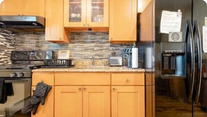 Una cocina con armarios de madera, un refrigerador de acero inoxidable, un microondas y una estufa.