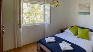 Makuuhuone, jossa on sänky, tyynyjä, yöpöytä, ikkuna ja riippuvalaisin.