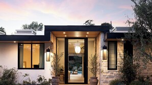 Une maison moderne avec une façade en pierre, de grandes fenêtres et une entrée accueillante.