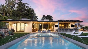Une maison moderne dotée d’une piscine, d’un espace extérieur aménagé et d’un bar.