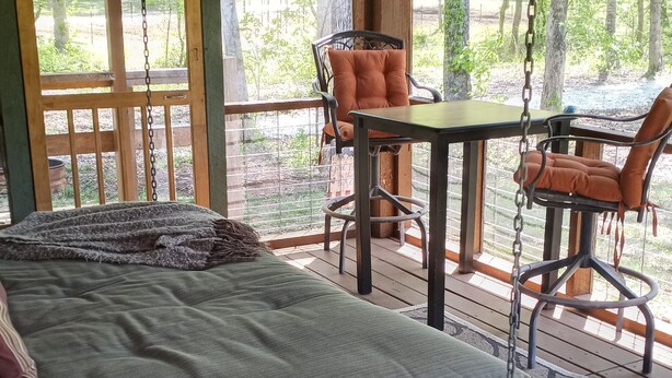 A wooden deck with a bed, chairs, and a table.