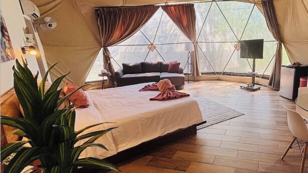 A spacious tent with a bed, a desk, and a chair.