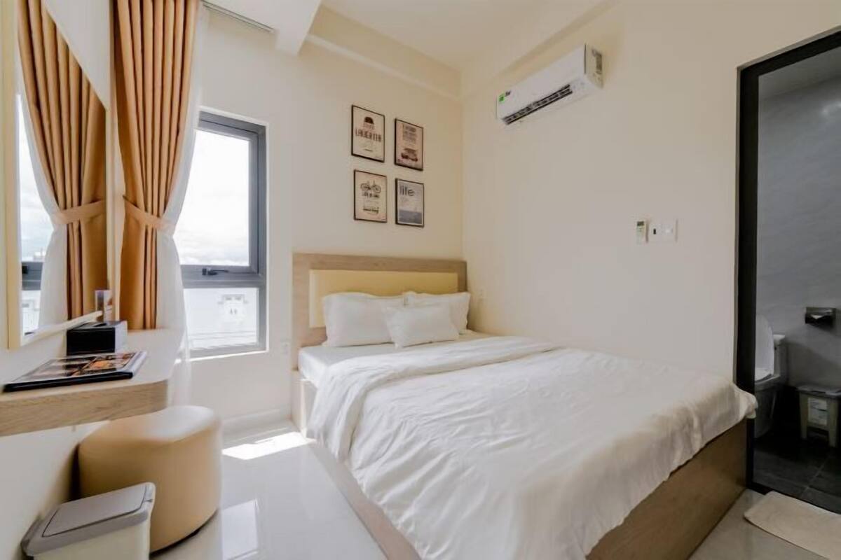 A bedroom with a bed, a desk, a chair, a window, and wall-mounted pictures.