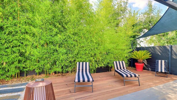 Une terrasse en bois avec deux chaises longues à rayures et une petite table.