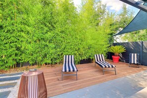 A wooden deck with two striped lounge chairs and a small table. - La Cabane du Cap - Jacuzzi & City Center Nearby (Aix-en-Provence)