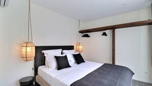 Une chambre à coucher avec un lit, des tables de chevet et des lampes suspendues.