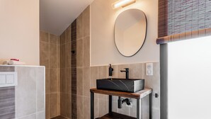 Une salle de bain moderne avec un lavabo rectangulaire, un miroir rond et un espace douche.