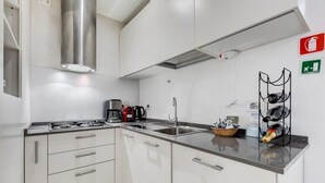 A modern kitchen with white cabinets, stainless steel appliances, and a black countertop. - Cozy Studio with private Outdoor Space - FromHometoRome (Roma)