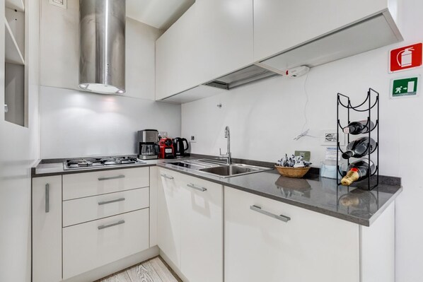 A modern kitchen with white cabinets, stainless steel appliances, and a black countertop.