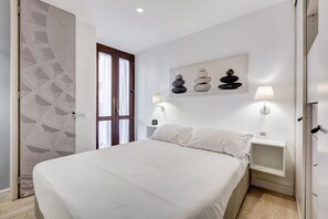 A bedroom with a bed, two bedside tables, a wall-mounted artwork, and a door with a geometric pattern.