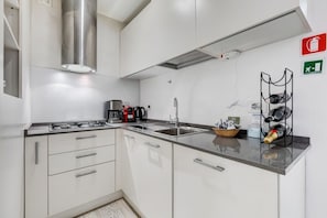 A modern kitchen with white cabinets, stainless steel appliances, and a black countertop.