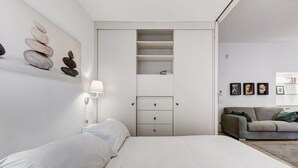 A minimalist bedroom with a bed, a built-in wardrobe, and a wall-mounted artwork. - Cozy Studio with private Outdoor Space - FromHometoRome (Roma)