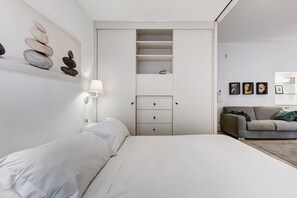 Une chambre à coucher au style minimaliste, avec un lit, une armoire intégrée et une œuvre d’art accrochée au mur.