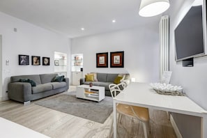 Un salon moderne avec un canapé gris, une table basse blanche et un coin repas comprenant une table et des chaises blanches.